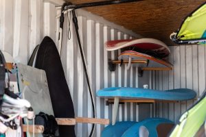 Interior of windsurf boards storage room in old rusty metal shipping container box with racks on wall - Yellowhead Storage